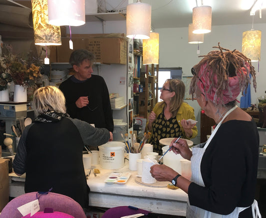 4 people around a table working with porcelain clay