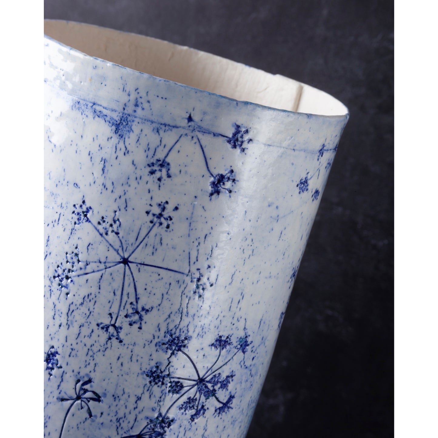 Detail of Porcelain lamp impressed with Queen Anne's Lace flowers. Photographed against a dark background