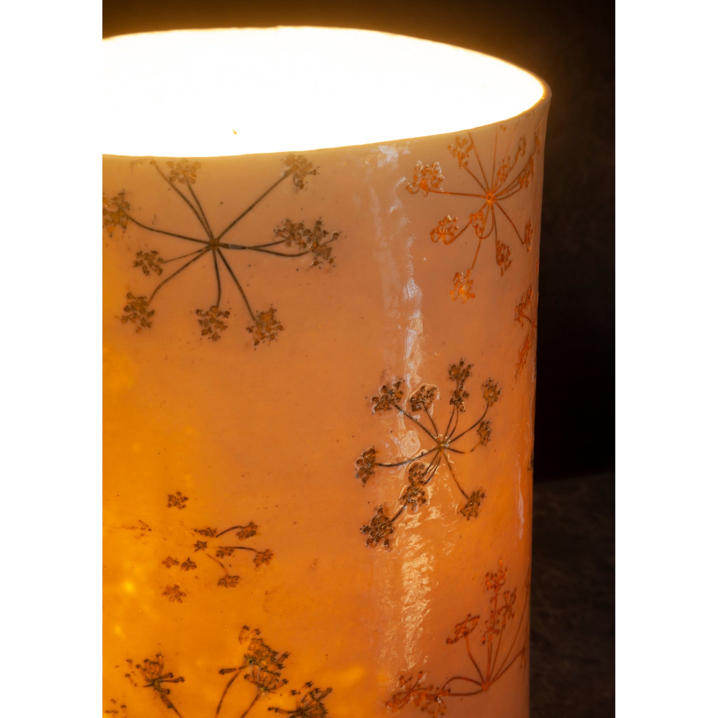 Detail of porcelain cylindrical lamp with cowparsley patterns on a dark background