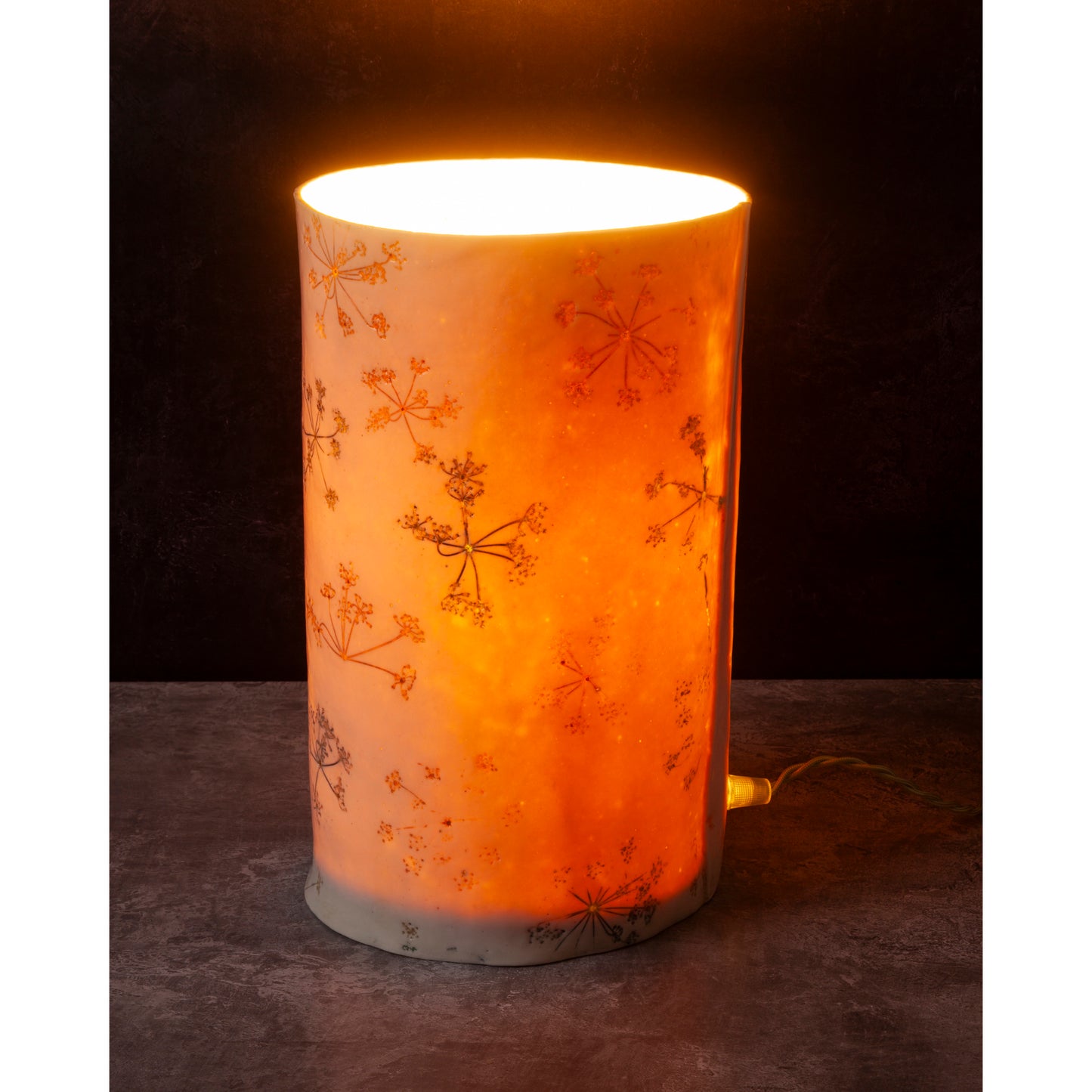 Decorative cylindrical lamp with floral patterns on a dark background