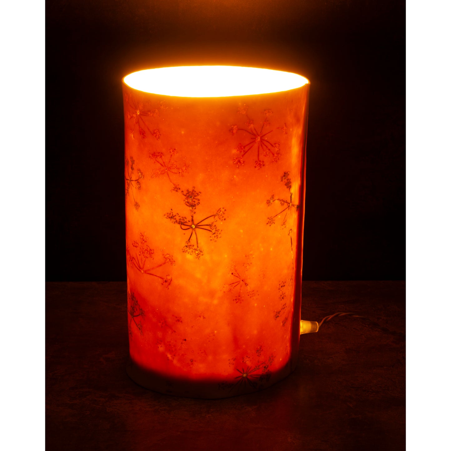 porcelain Cylindrical lamp with a warm glow on a dark background