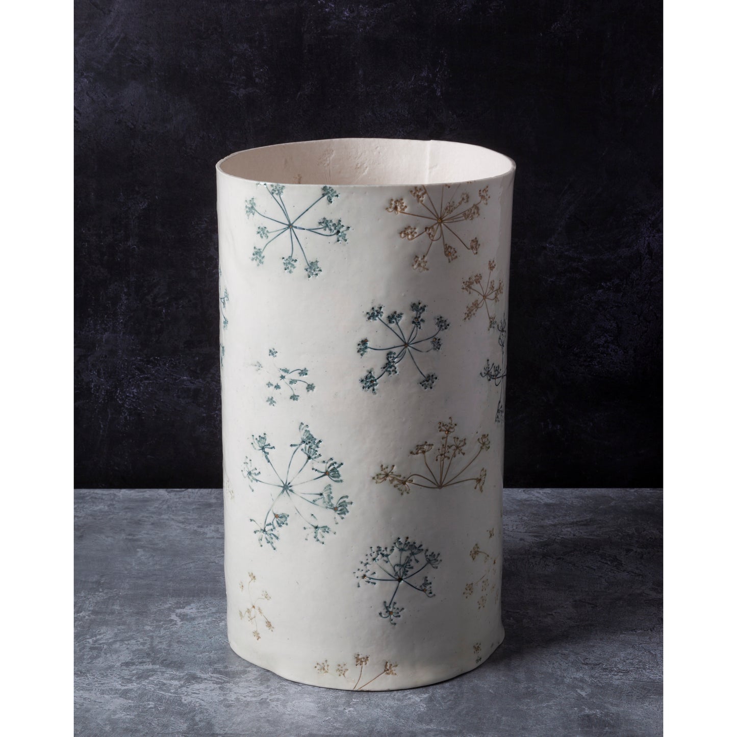 Cylindrical lamp unlit with floral pattern on a dark background