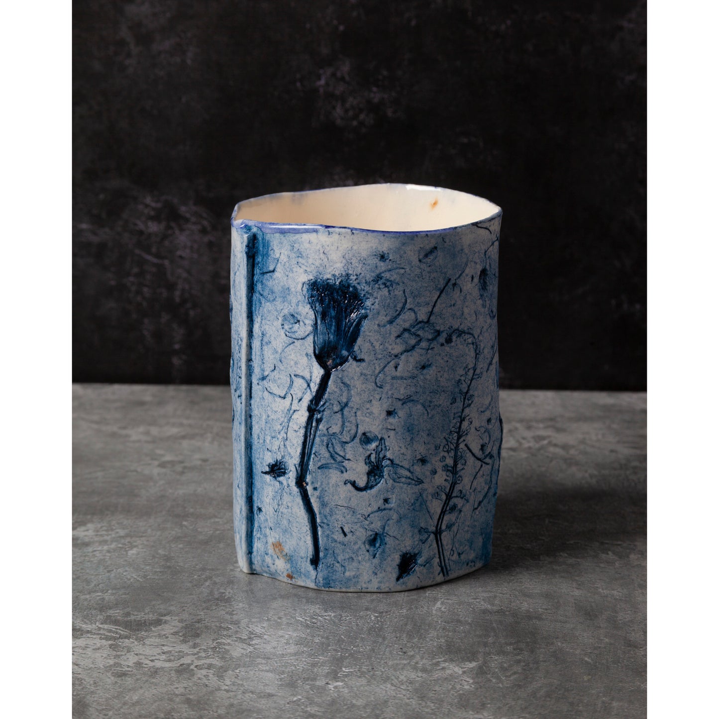 Cylindrical ceramic vase with blue abstract patterns on a dark background