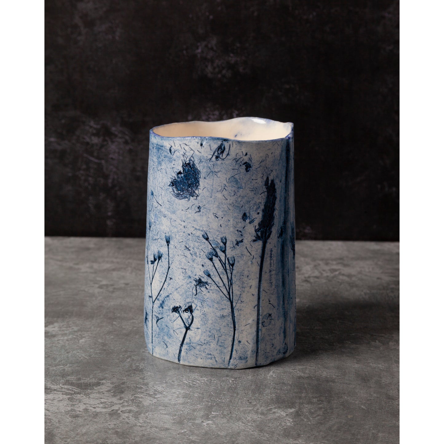 Cylindrical ceramic vase with blue floral patterns on a dark background