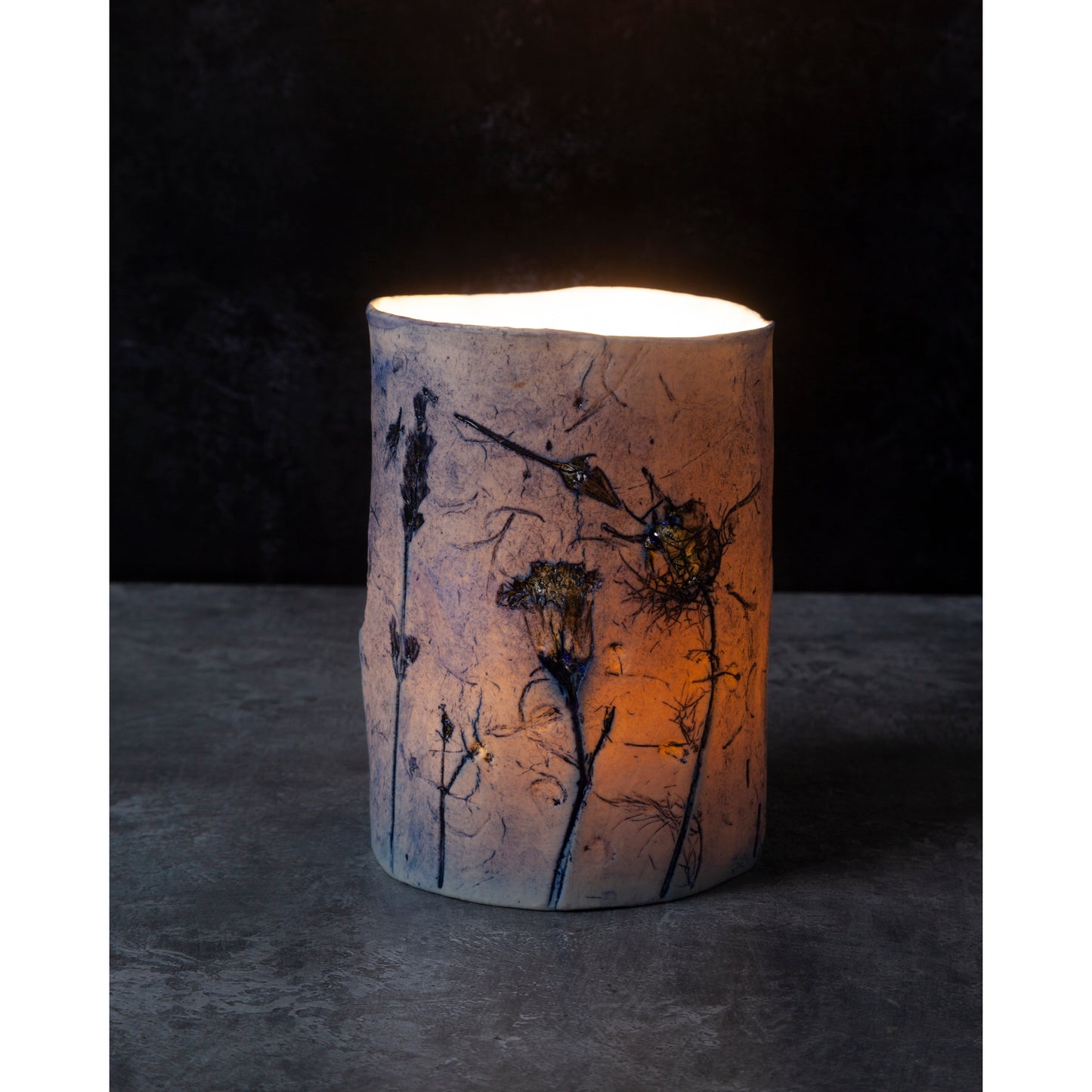Cylindrical ceramic night light with floral patterns on a dark background