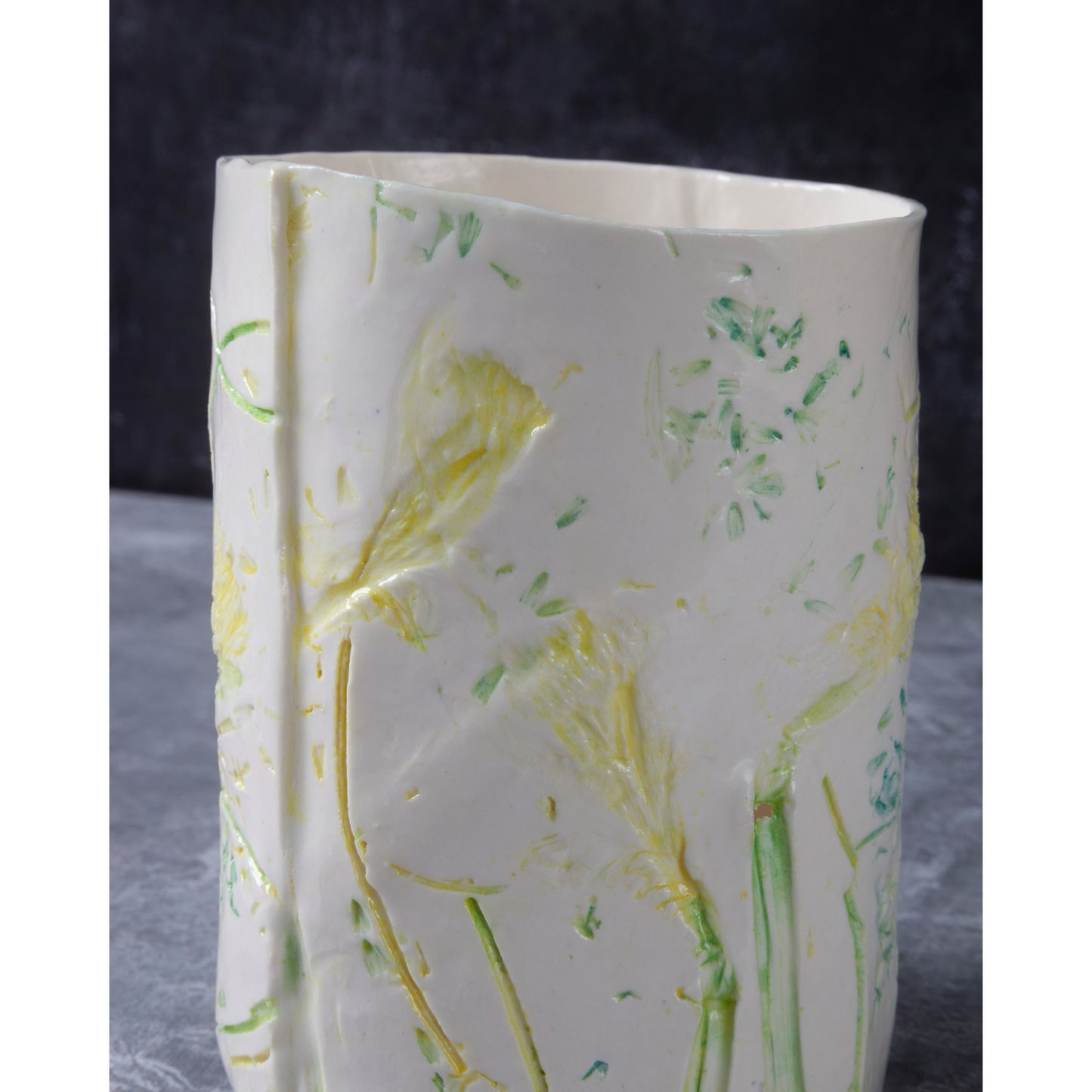 Detail of White porcelain ceramic vase with daffodil floral design. Photographed against a dark background