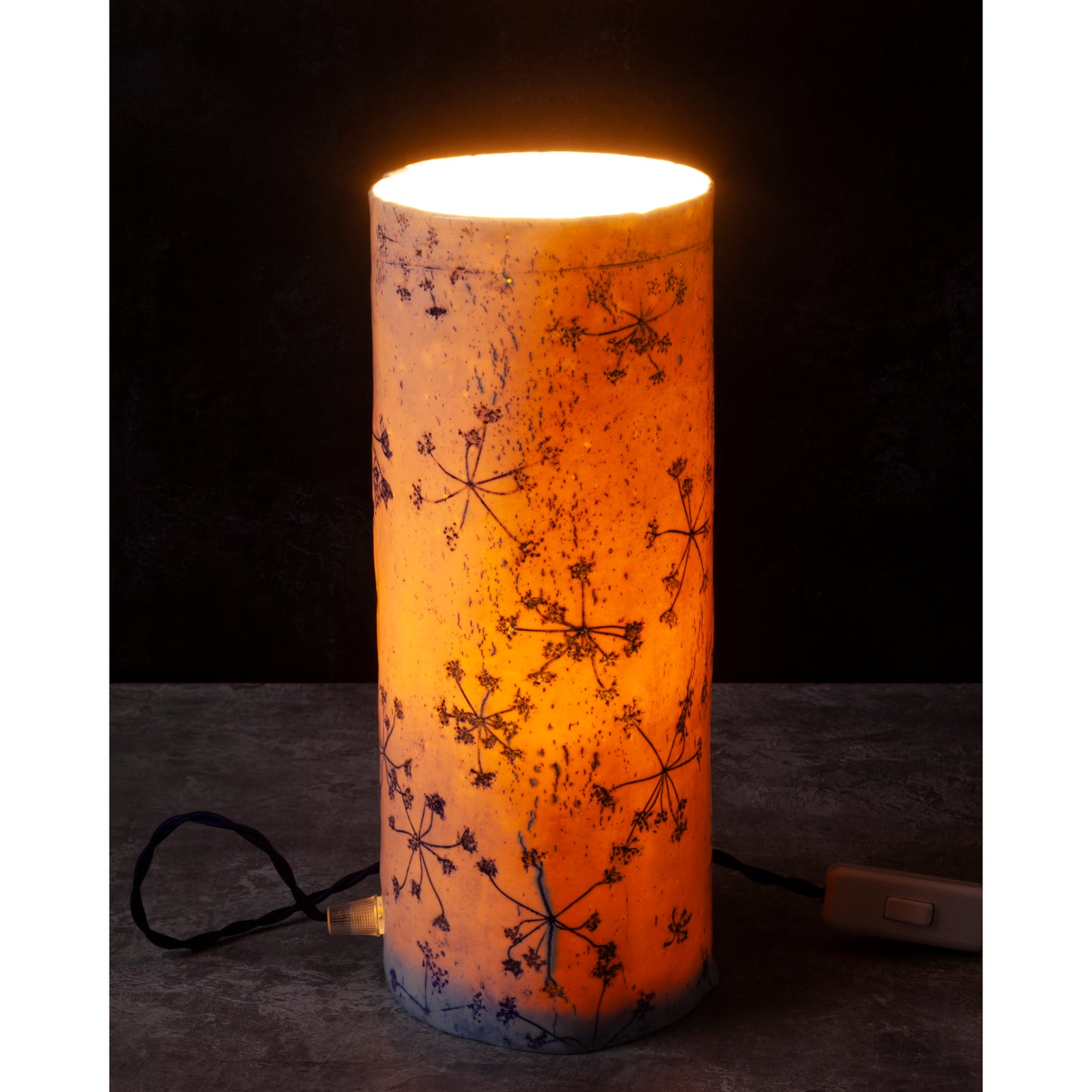 Porcelain lamp impressed with Queen Anne's Lace flowers. Photographed against a dark background