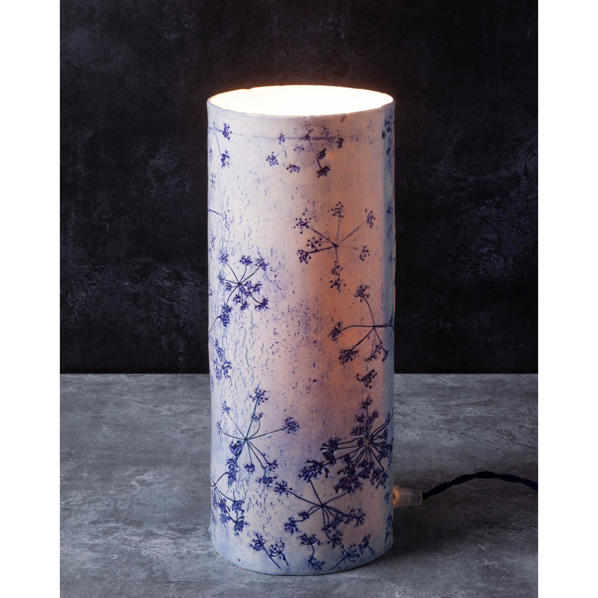 Porcelain lamp impressed with Queen Anne's Lace flowers. Photographed against a dark background