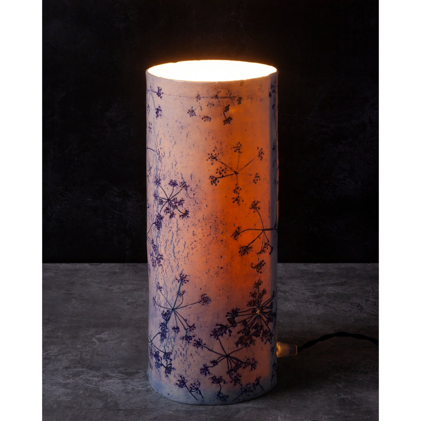 Porcelain lamp impressed with Queen Anne's Lace flowers. Photographed against a dark background