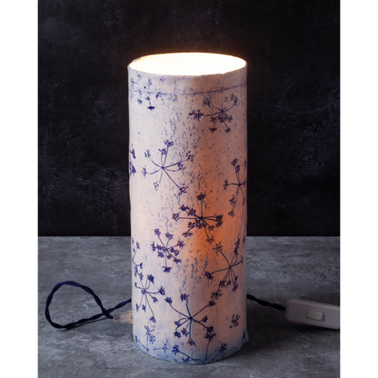 Porcelain lamp impressed with Queen Anne's Lace flowers. Photographed against a dark background. 