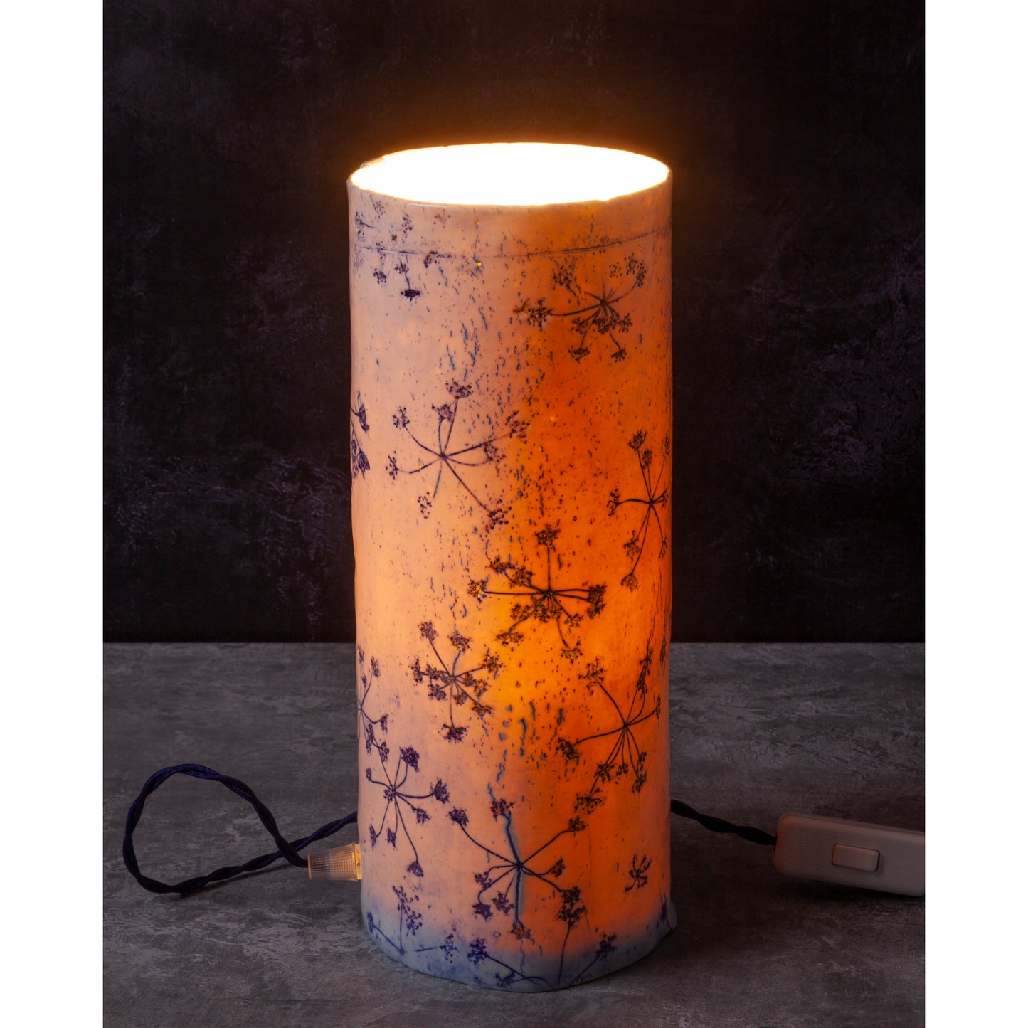 Porcelain lamp impressed with Queen Anne's Lace flowers. Photographed against a dark background