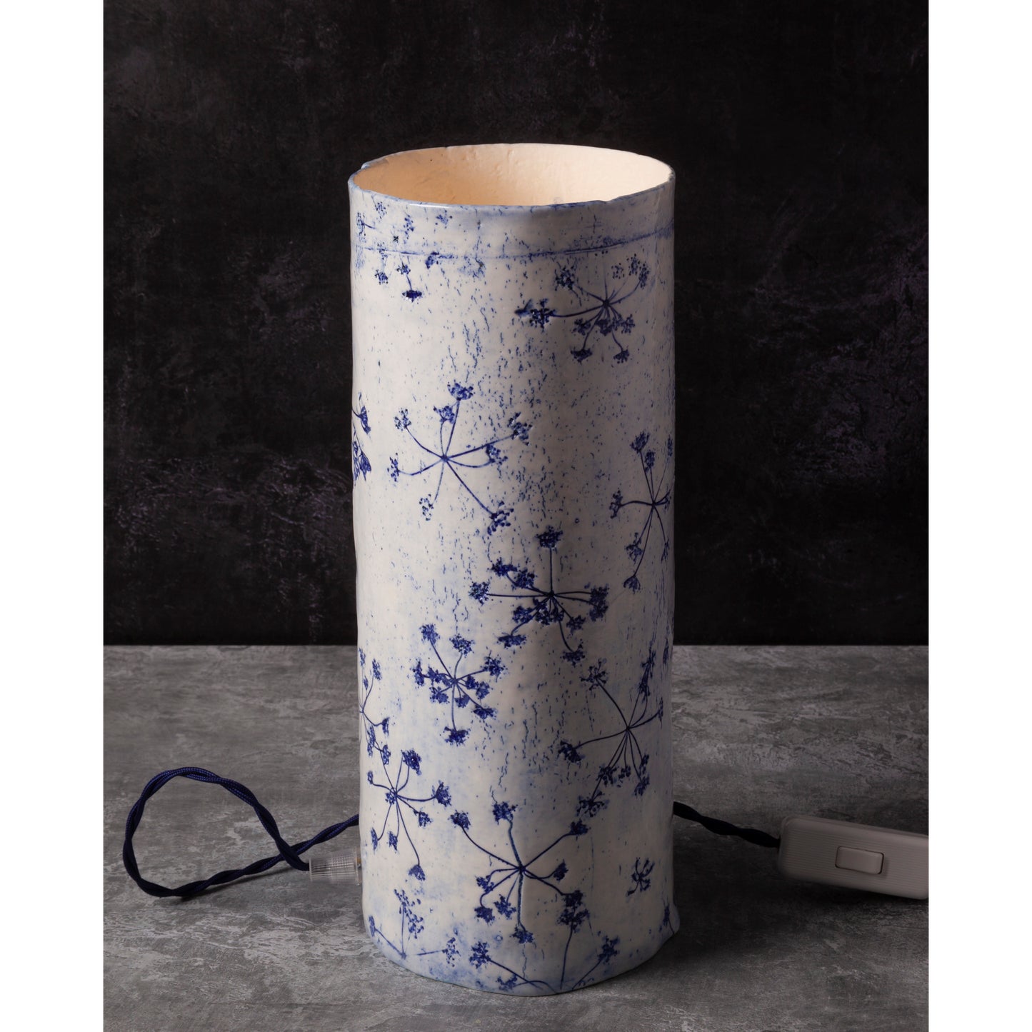 Porcelain lamp impressed with Queen Anne's Lace flowers. Photographed against a dark background