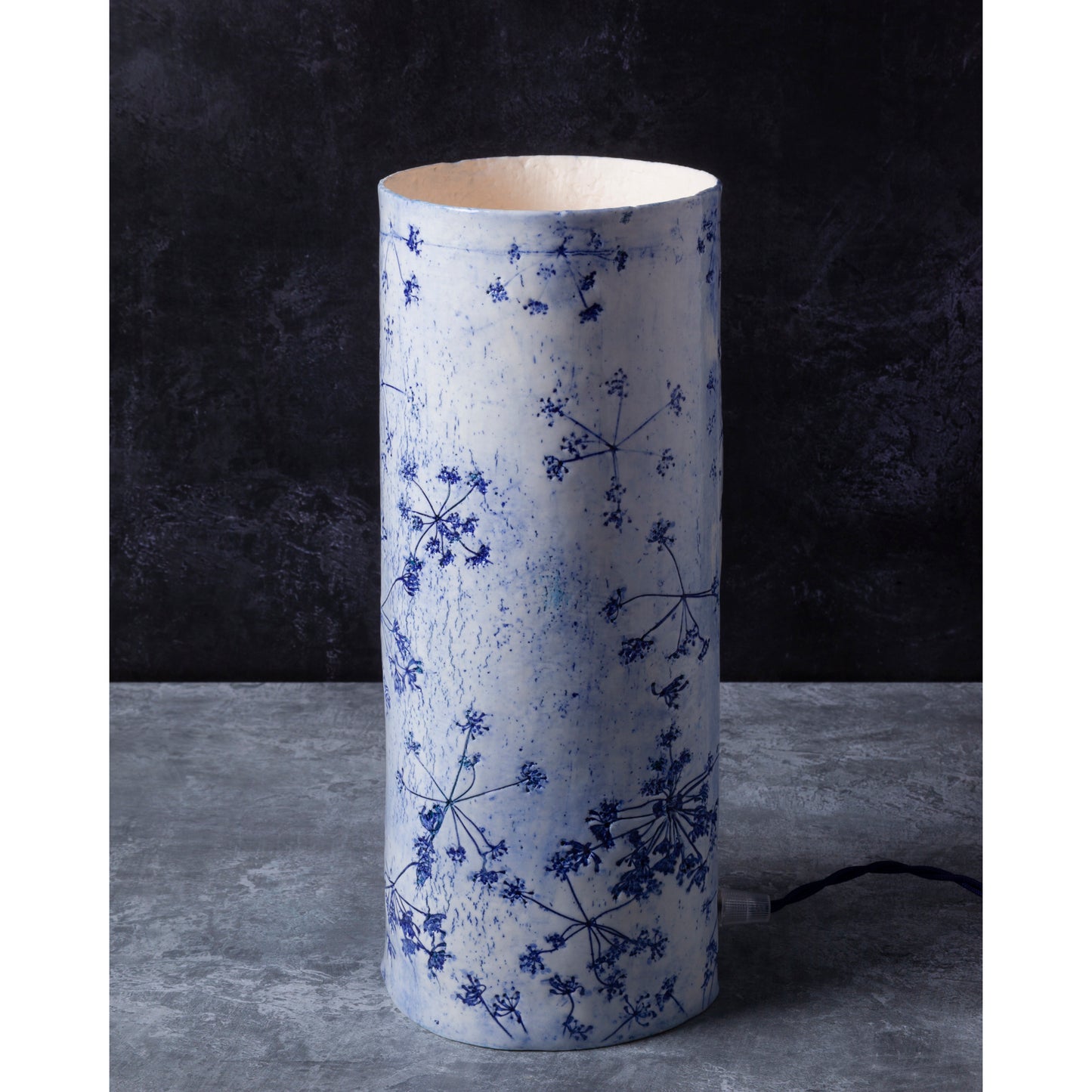 Porcelain lamp impressed with Queen Anne's Lace flowers. Photographed against a dark background