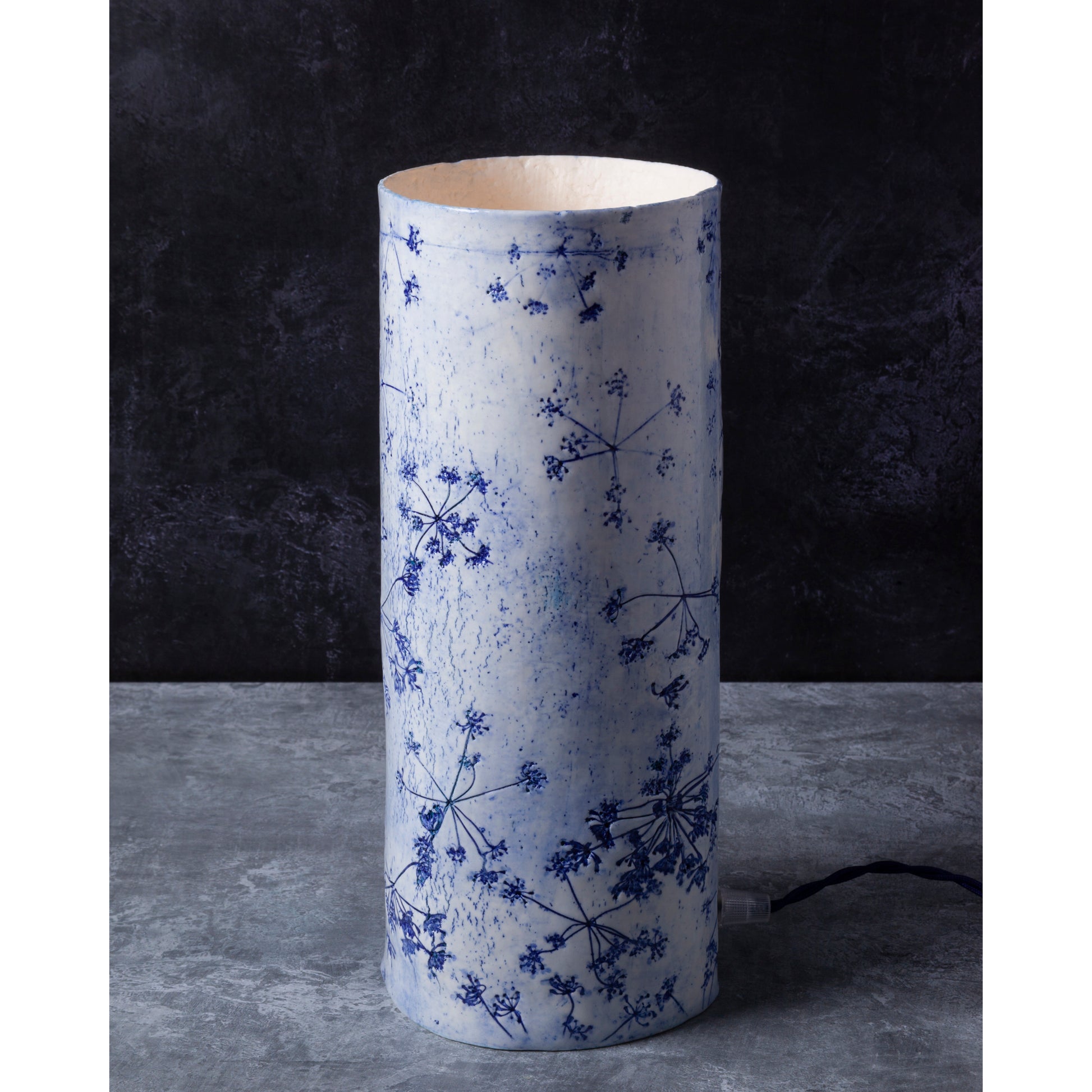 Porcelain lamp impressed with Queen Anne's Lace flowers. Photographed against a dark background