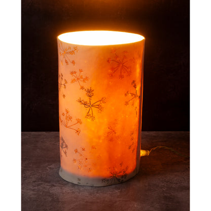 Decorative cylindrical lamp with floral patterns on a dark background