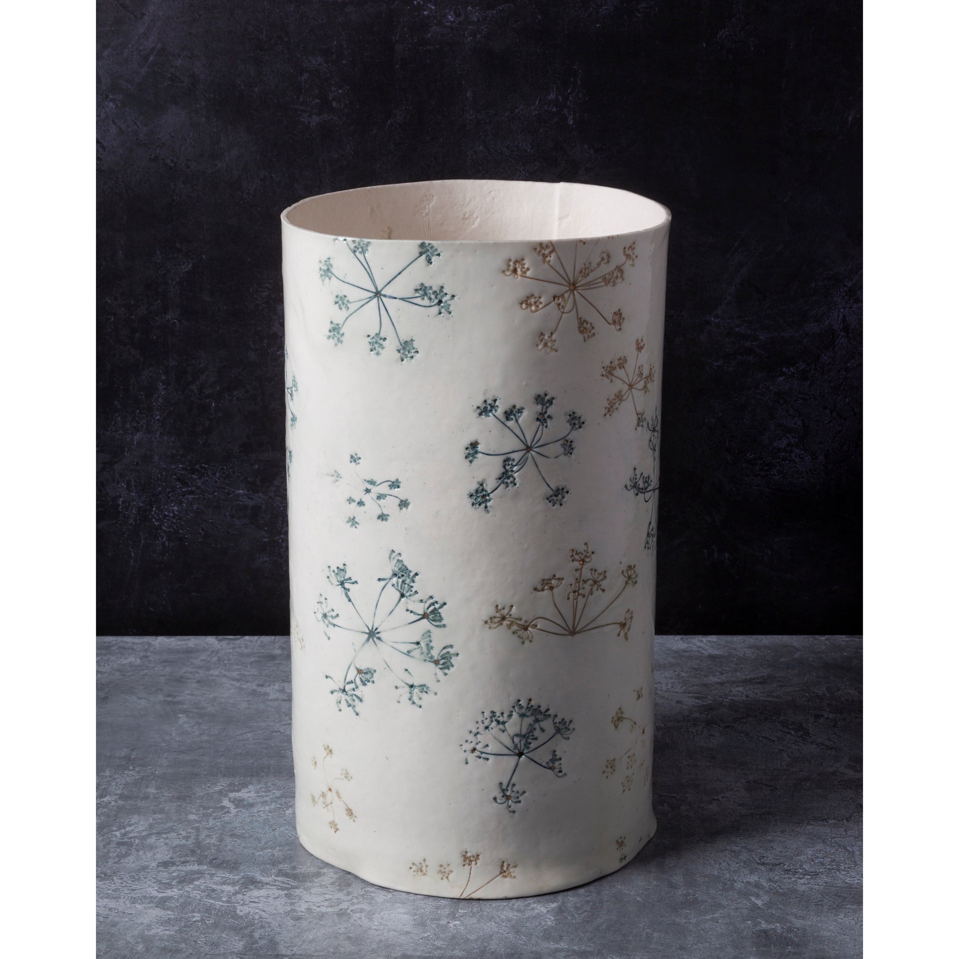 Cylindrical lamp unlit with floral pattern on a dark background