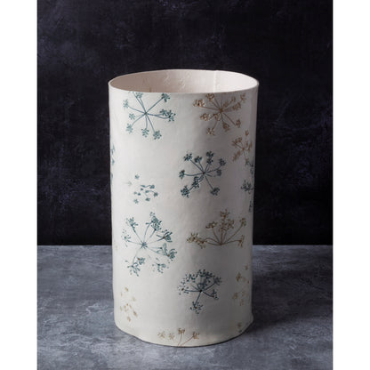 Cylindrical lamp unlit with floral pattern on a dark background