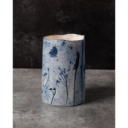 Cylindrical ceramic vase with blue floral patterns on a dark background