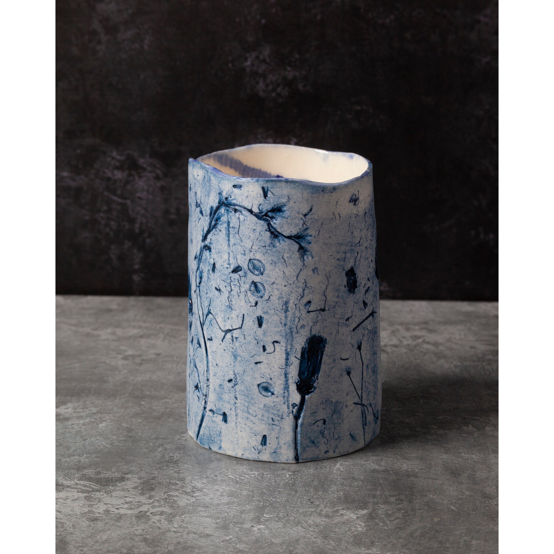 Cylindrical ceramic vase with abstract blue patterns on a dark background