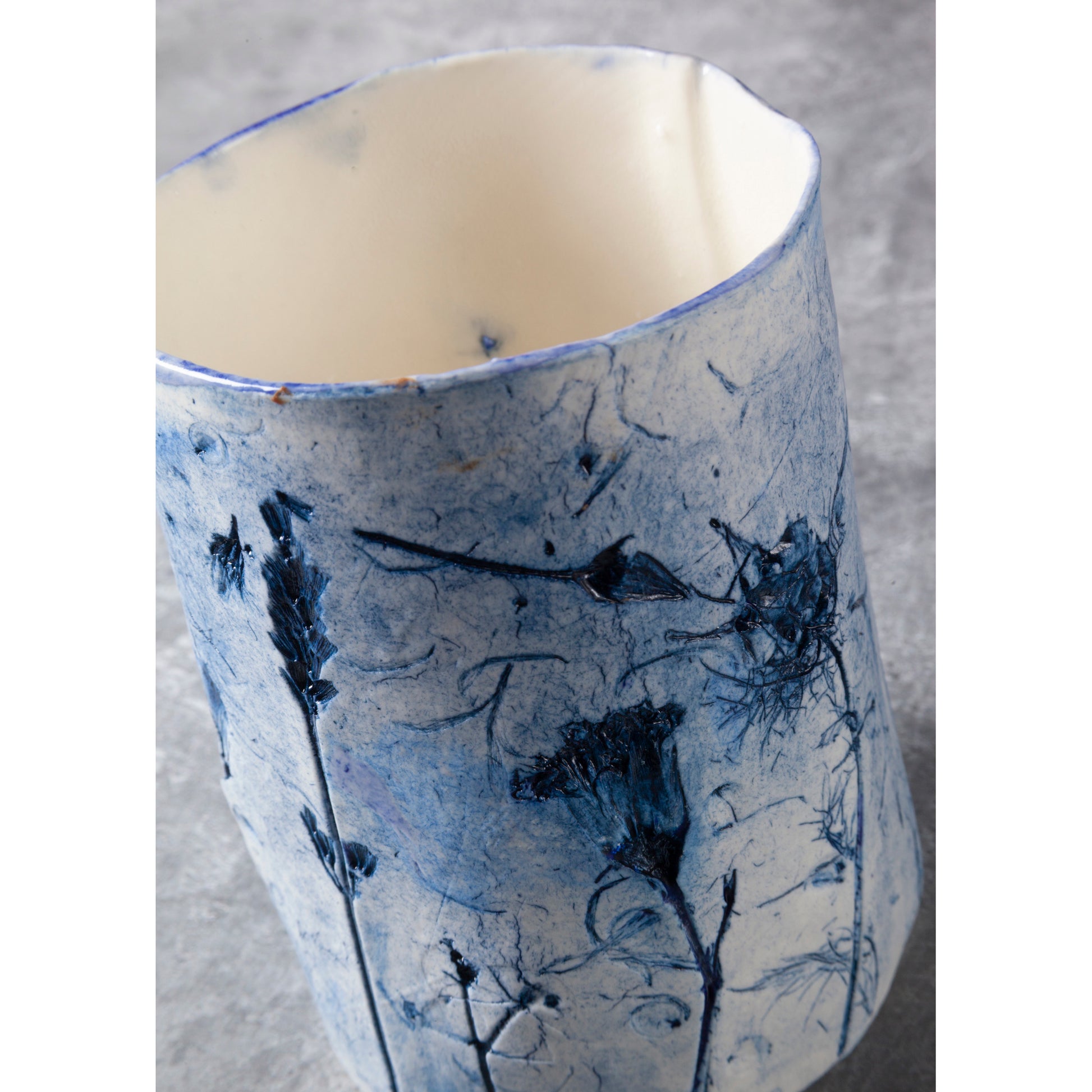 Ceramic vessel with blue floral pattern on a gray background
