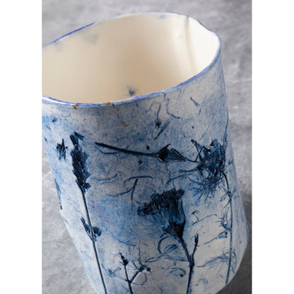 Ceramic vessel with blue floral pattern on a gray background
