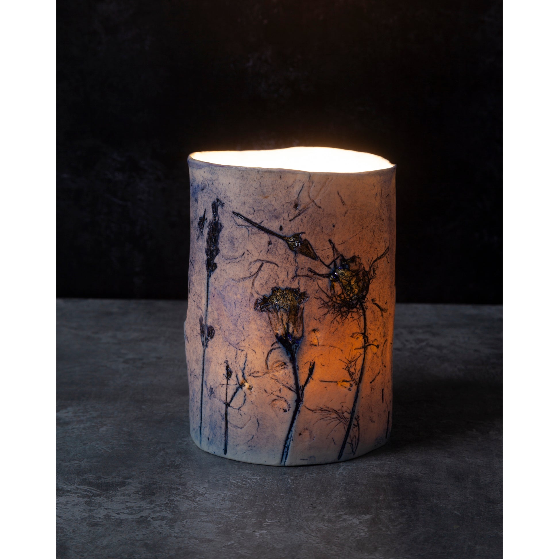 Cylindrical ceramic night light with floral patterns on a dark background