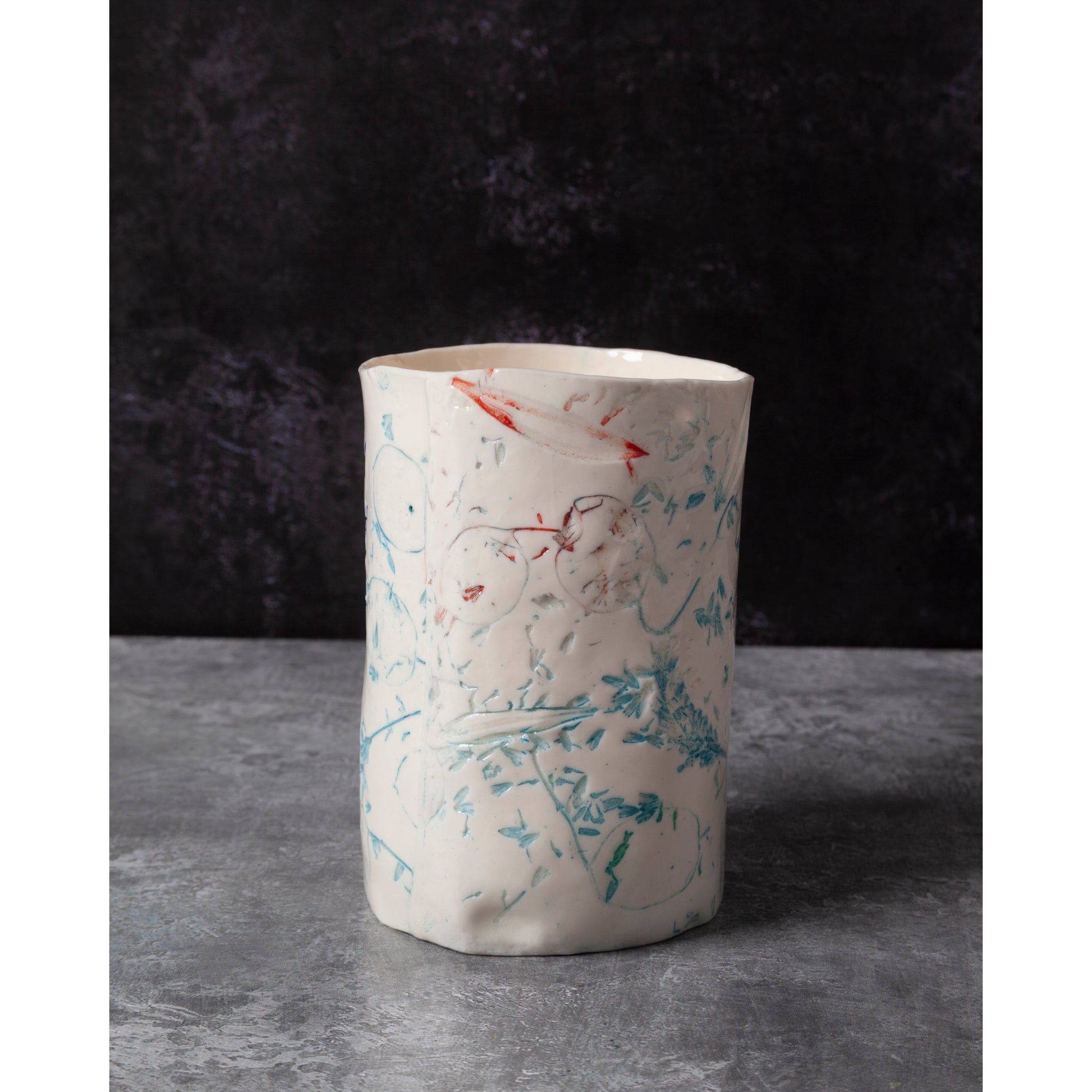 Cylindrical porcelain ceramic vase with abstract designs  using honesty seed heads, lavender, grasses and olive leaves in a dark background