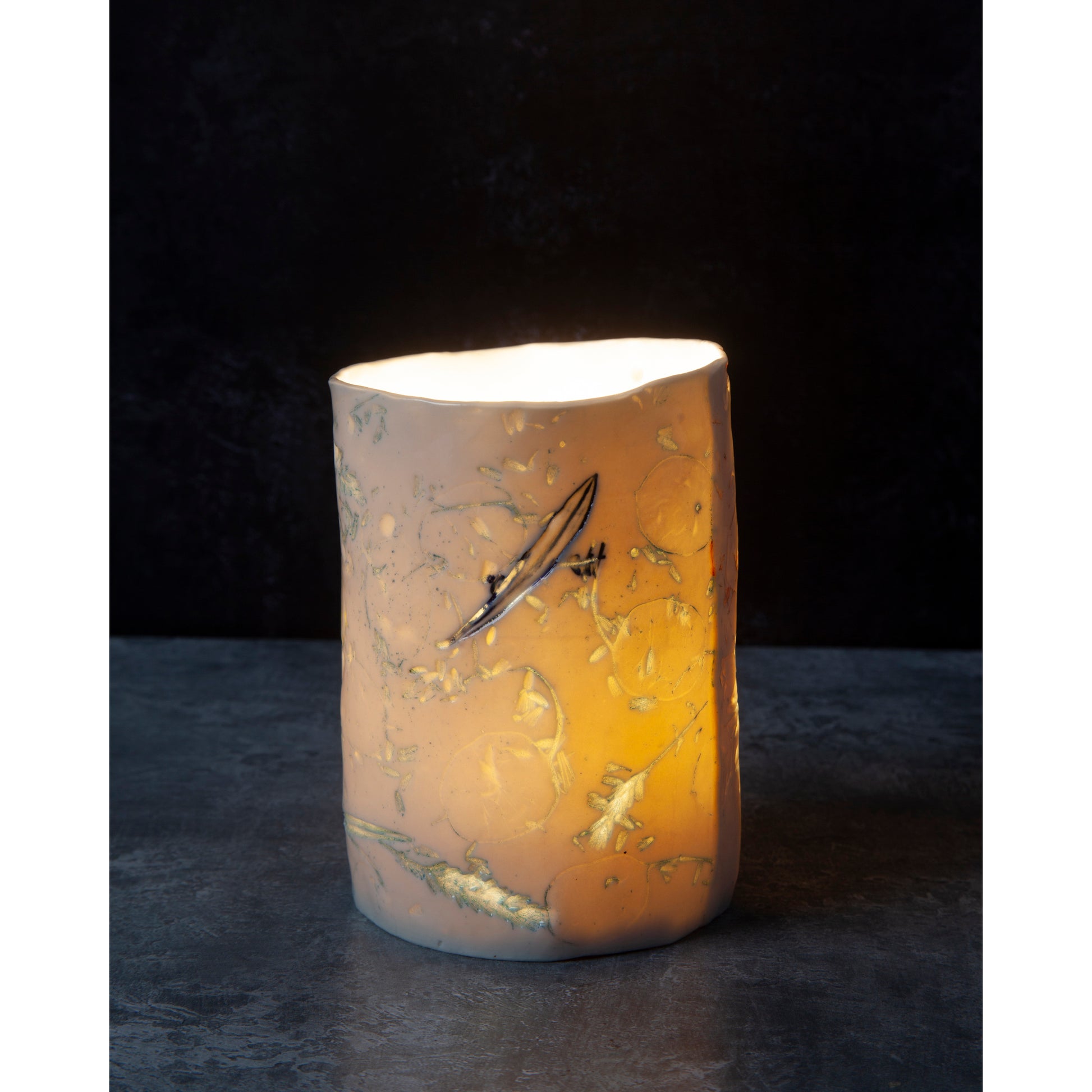 Decorative porcelain candle / vase with abstract designs  using honesty seed heads, lavender, grasses and olive leaves photographed in a dark background