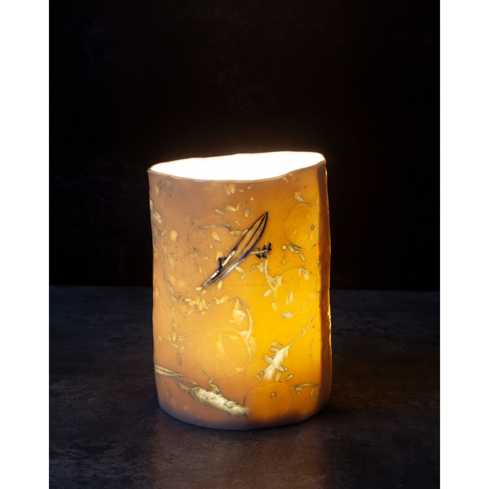 Cylindrical porcelain ceramic vase with abstract designs  using honesty seed heads, lavender, grasses and olive leaves photographed against a dark background