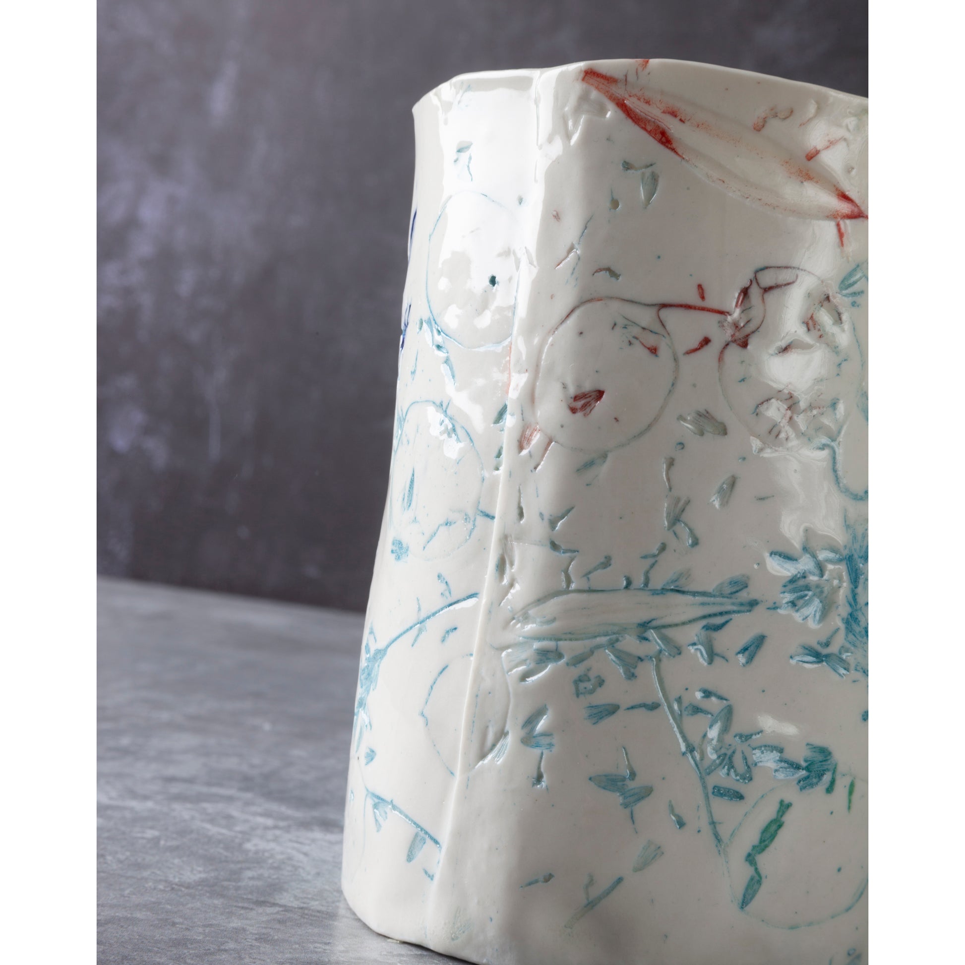 Detail of cylindrical porcelain ceramic vase with abstract designs  using honesty seed heads, lavender, grasses and olive leaves photographed in a dark background