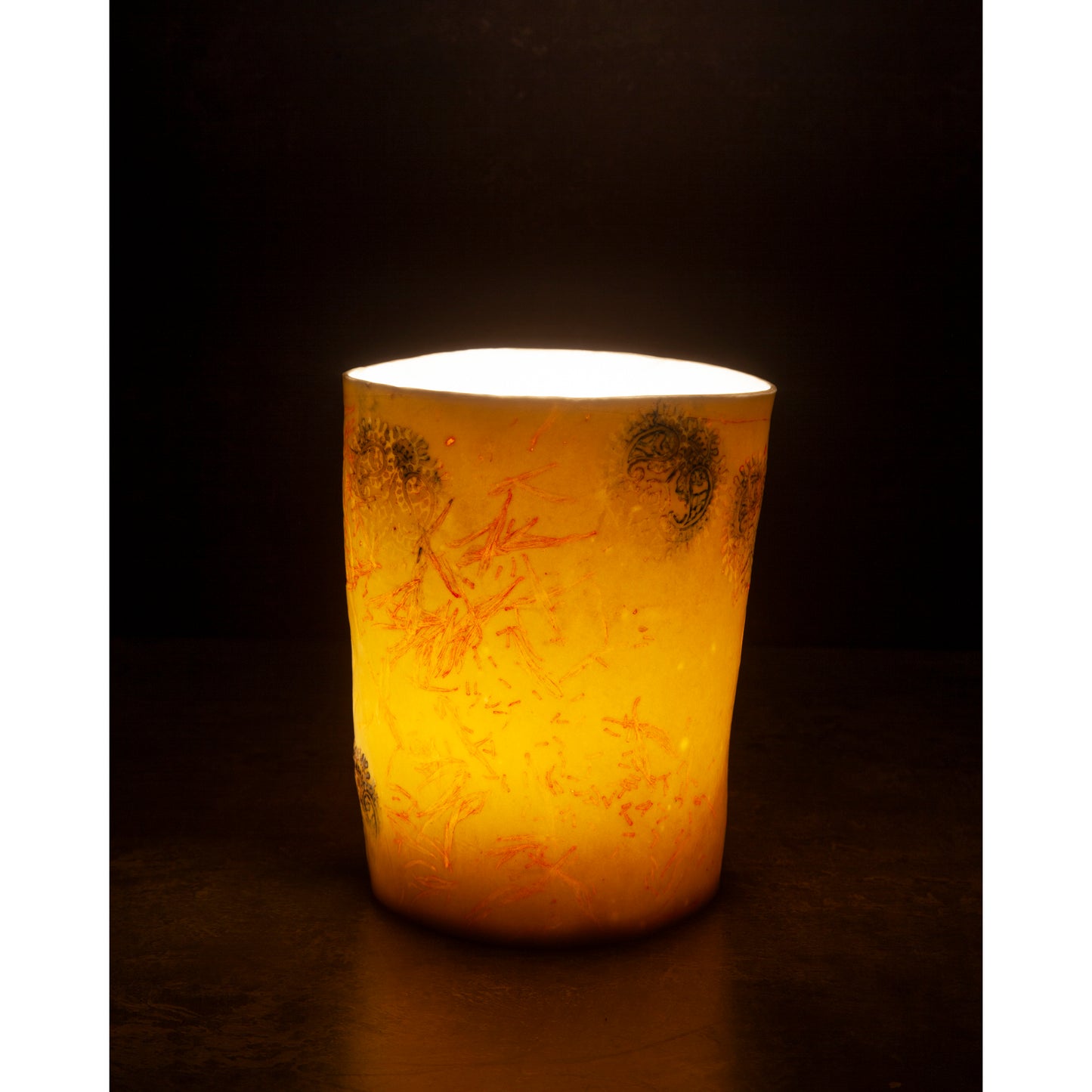 Yellow candle with intricate patterns on a dark background