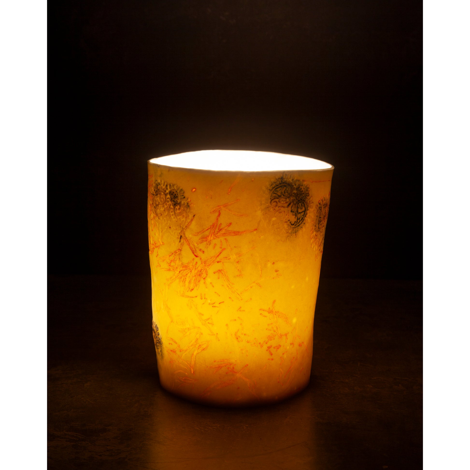 Yellow candle with intricate patterns on a dark background