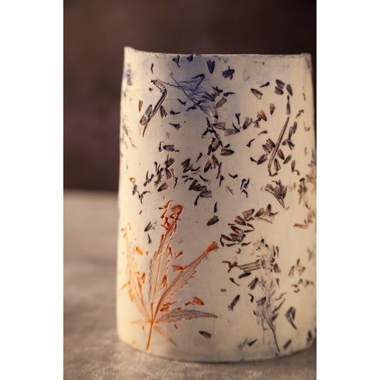 Ceramic vase with lavender, grasses and leaf patterns on a white porcelain surface. High lights of blue and orange