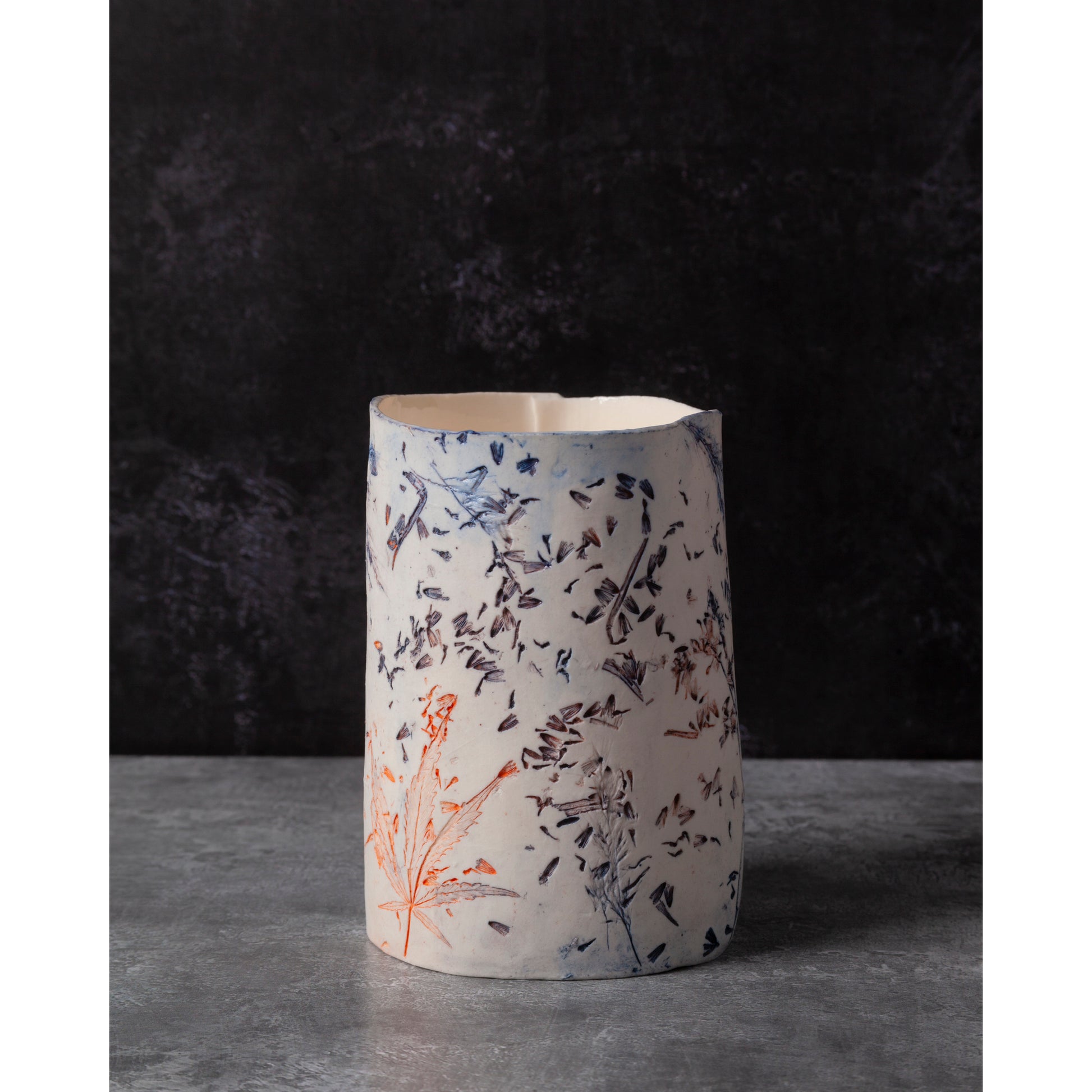 Ceramic vase with lavender, grasses and leaf patterns on a white porcelain surface. High lights of blue and orange