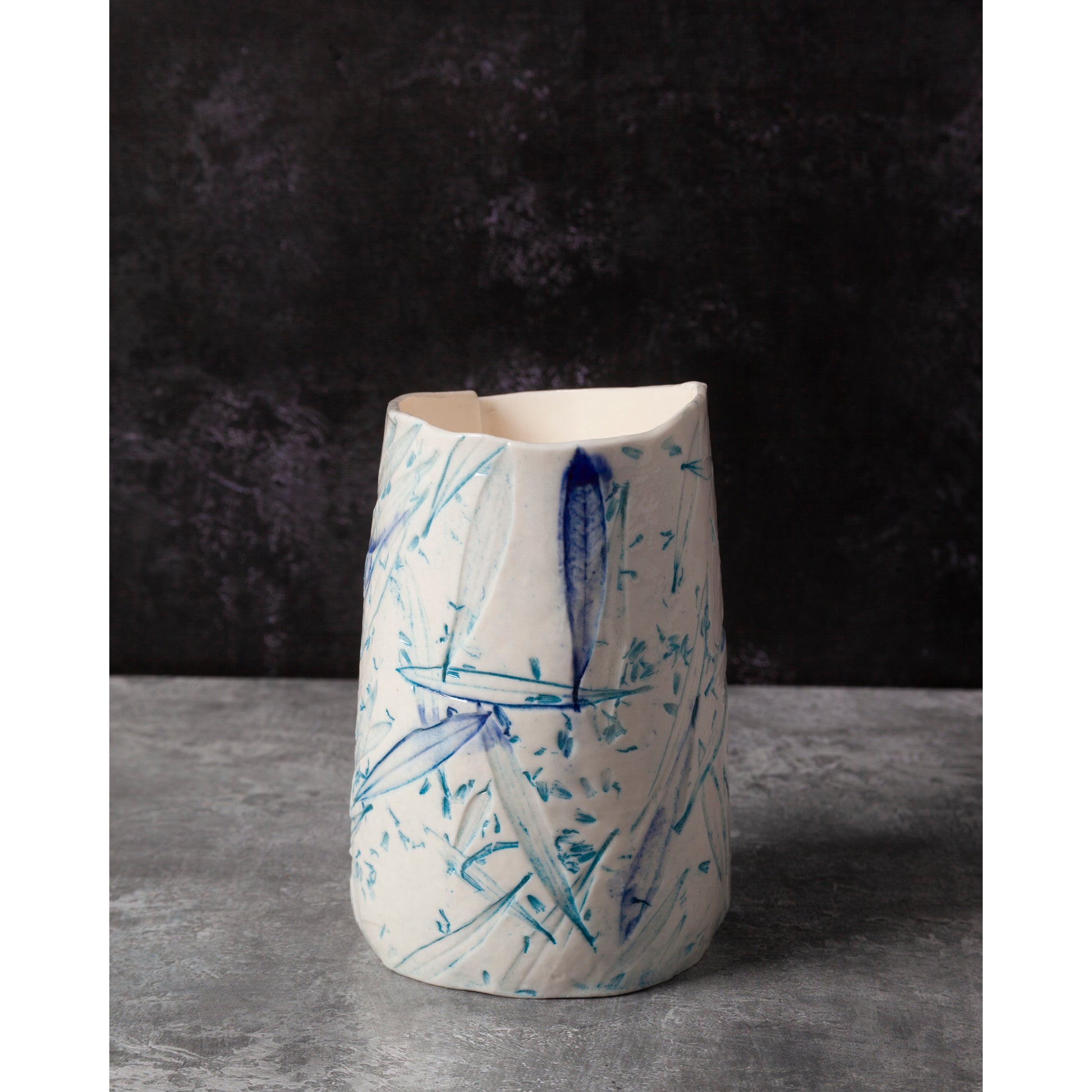 Ceramic night light / vase with blue abstract patterns using olive leaves and lavender seeds on a dark background