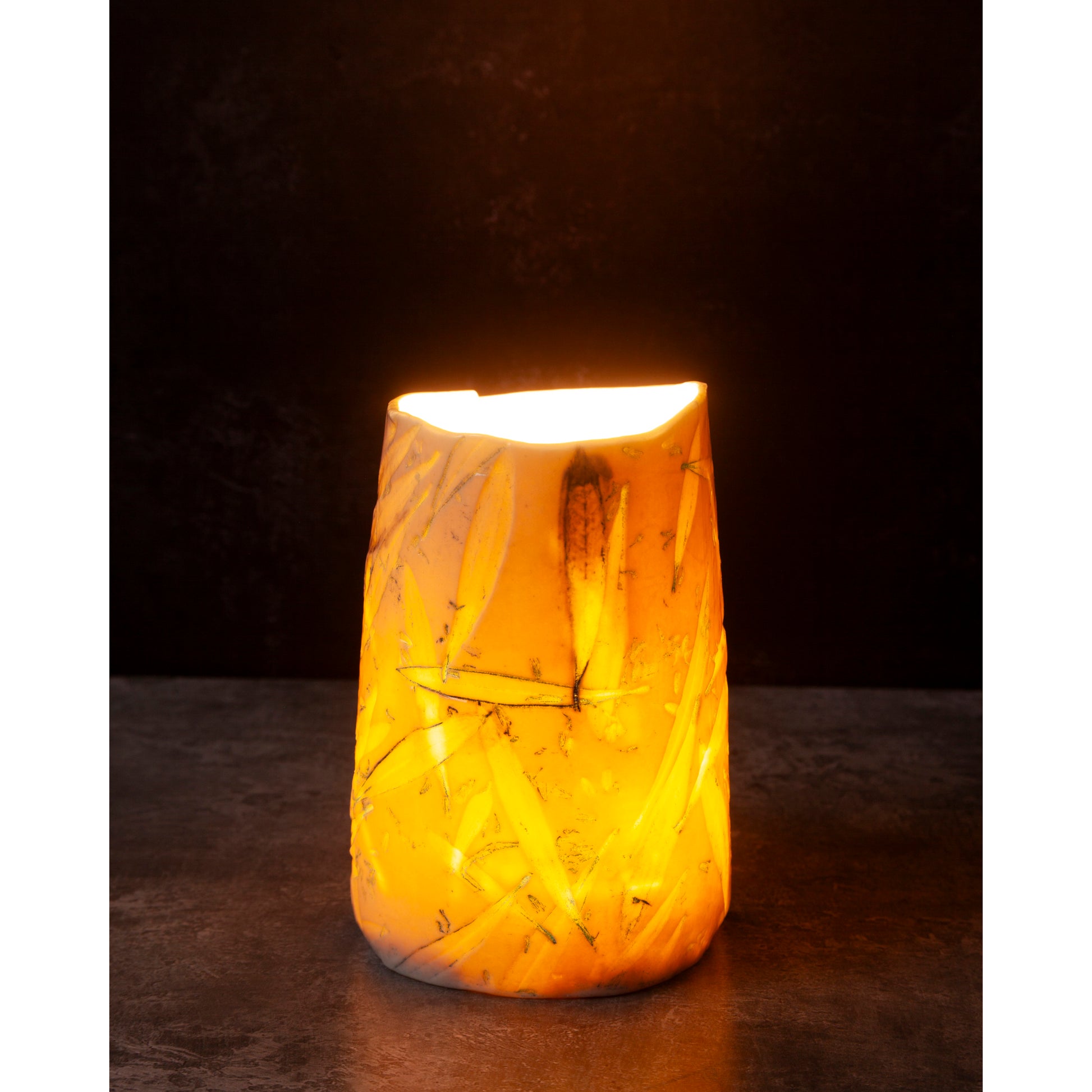 Ceramic night light / vase with blue abstract patterns using olive leaves and lavender seeds glowing softly against a dark background.