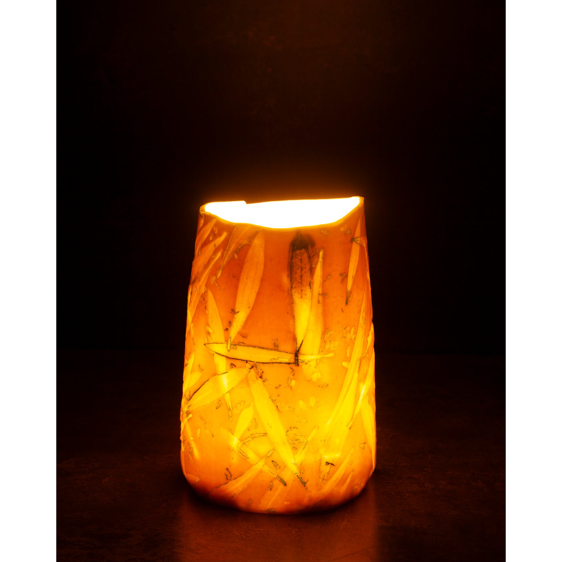 Ceramic night light / vase with blue abstract patterns using olive leaves and lavender seeds glowing softly against a dark background.
