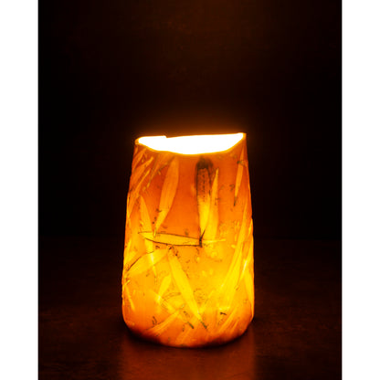 Ceramic night light / vase with blue abstract patterns using olive leaves and lavender seeds glowing softly against a dark background.