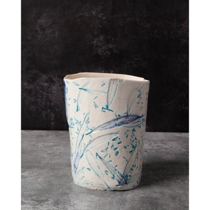 Ceramic night light / vase with blue abstract patterns using olive leaves and lavender seeds against a dark background.