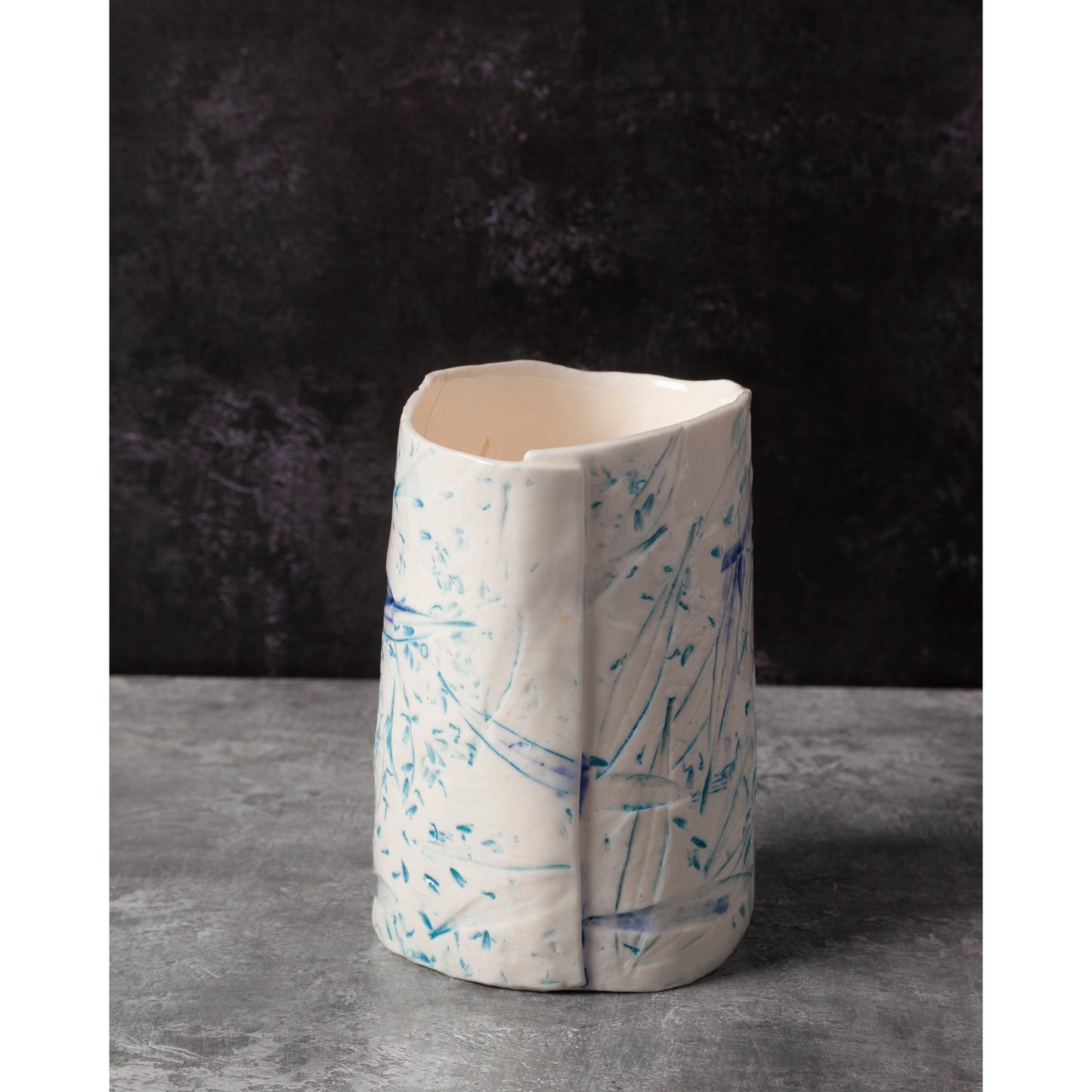 Ceramic night light / vase with blue abstract patterns using olive leaves and lavender seeds against a dark background.