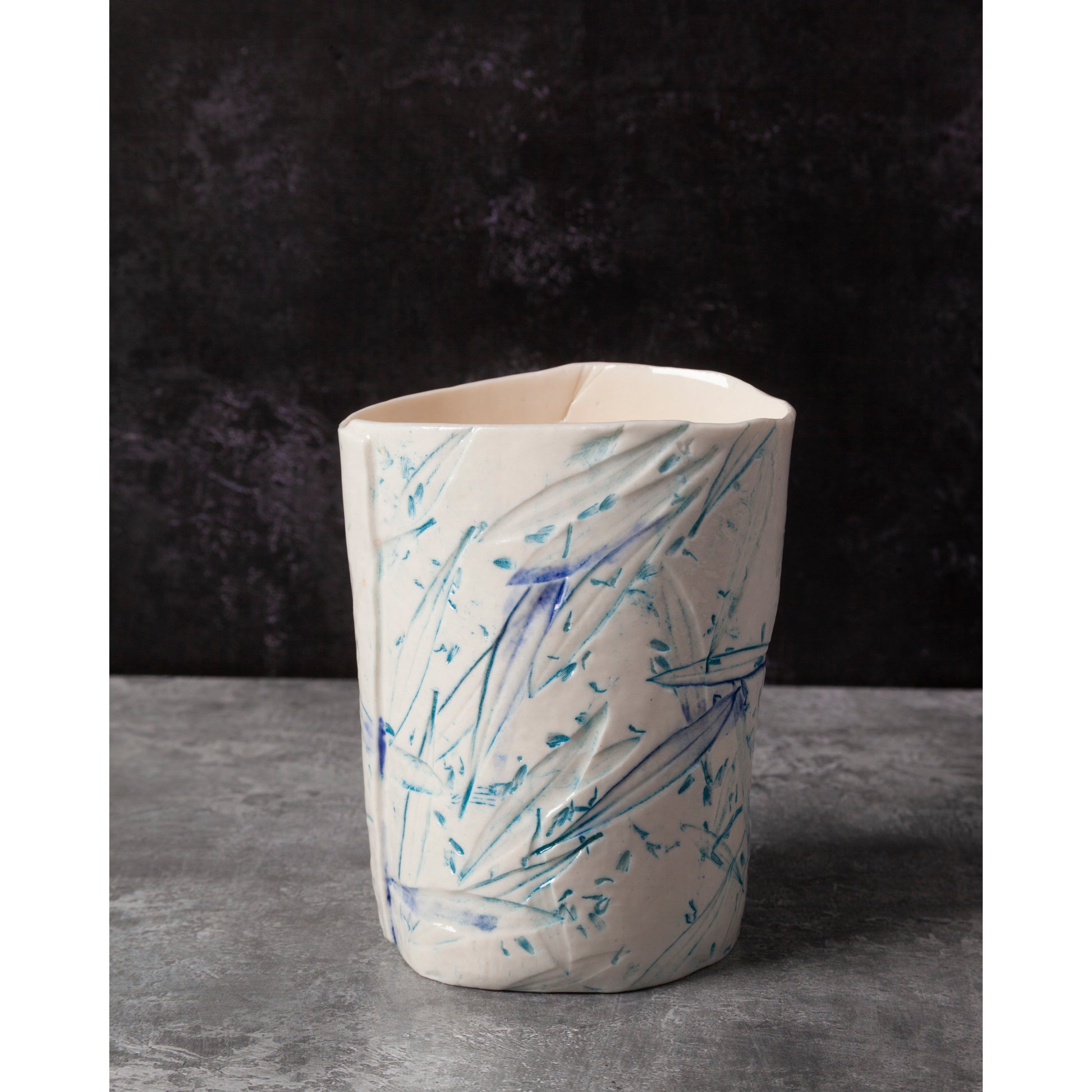 Ceramic night light / vase with blue abstract patterns using olive leaves and lavender seeds against a dark background.