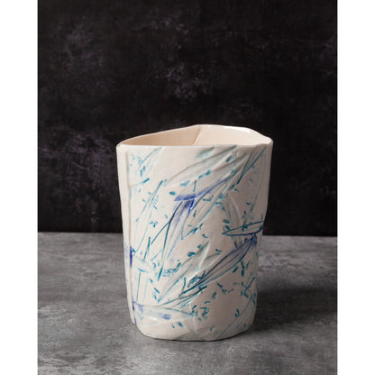 Ceramic night light / vase with blue abstract patterns using olive leaves and lavender seeds against a dark background.