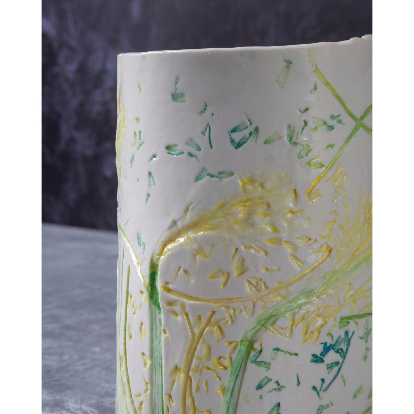 Close-up of a ceramic vase / night light a with green and yellow daffodil patterns. Photographed against a dark background
