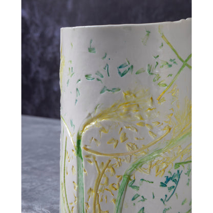 Close-up of a ceramic vase / night light a with green and yellow daffodil patterns. Photographed against a dark background