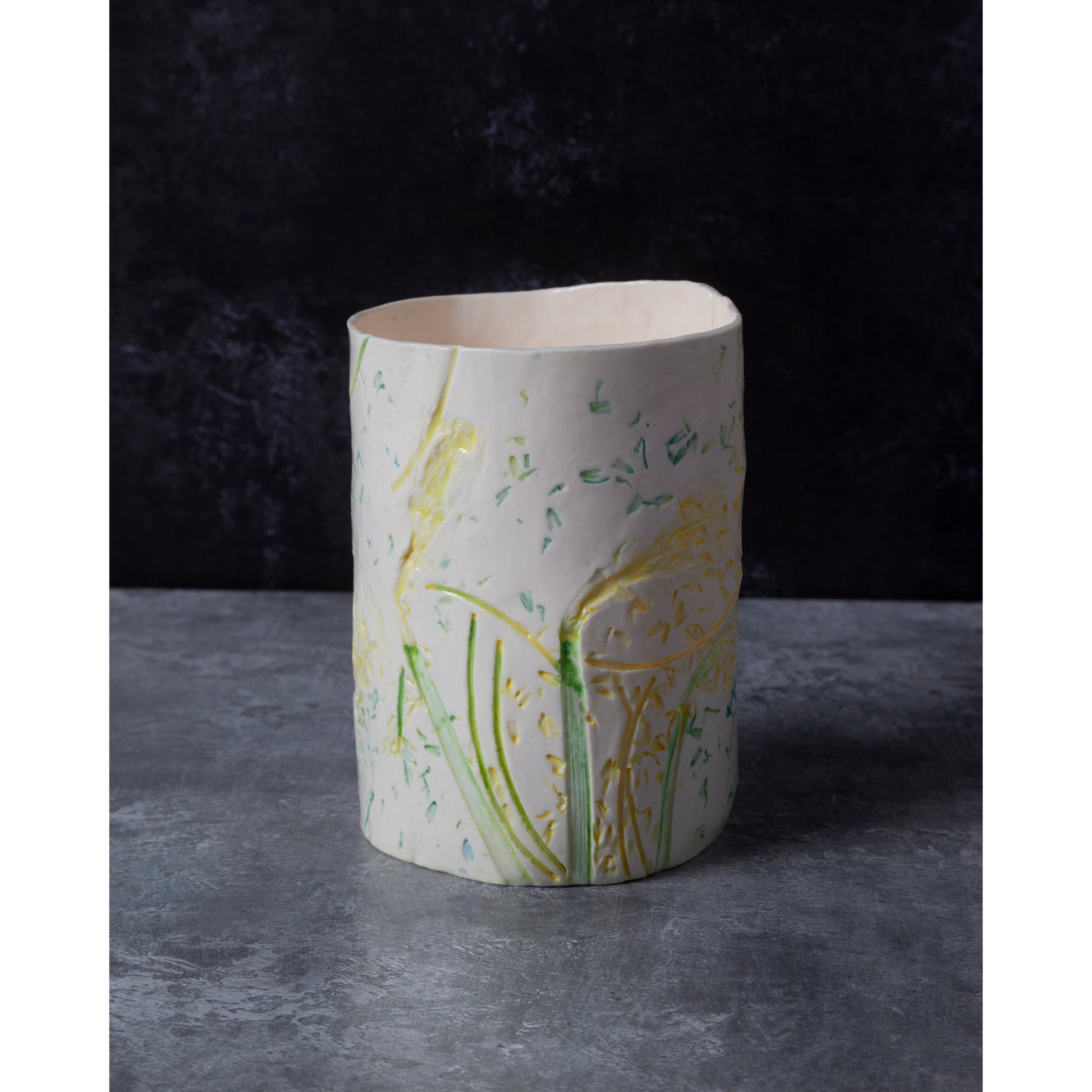 Cylindrical ceramic vase / night light with  green and yellow daffodil patterns on a dark background