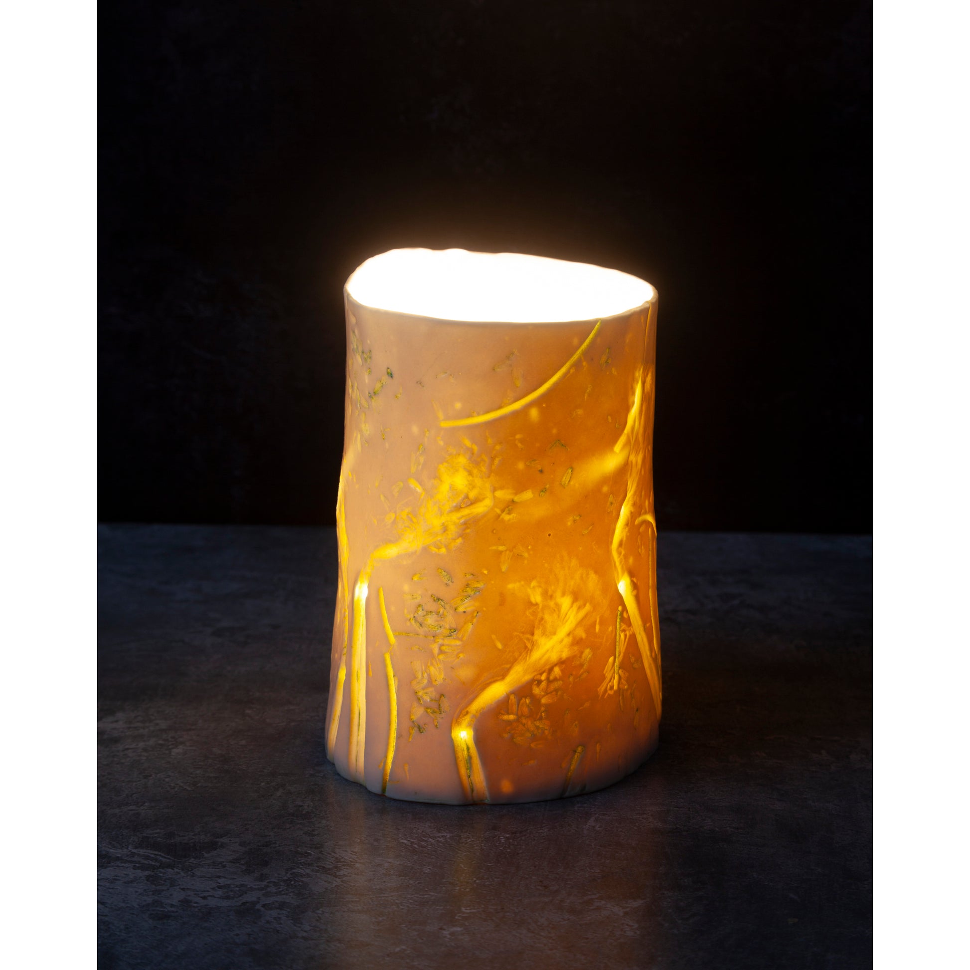 Decorative porcelain tea light - vase with golden colour. Photographed agains a dark background
