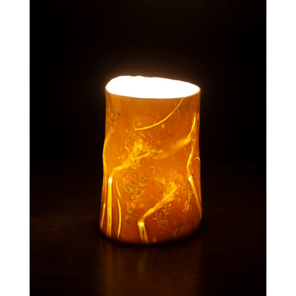 Cylindrical porcelain night light -vase with a warm glow. Photographed against a dark background