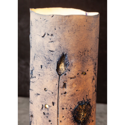 Cylindrical candle with textured surface and decorative elements on a dark background