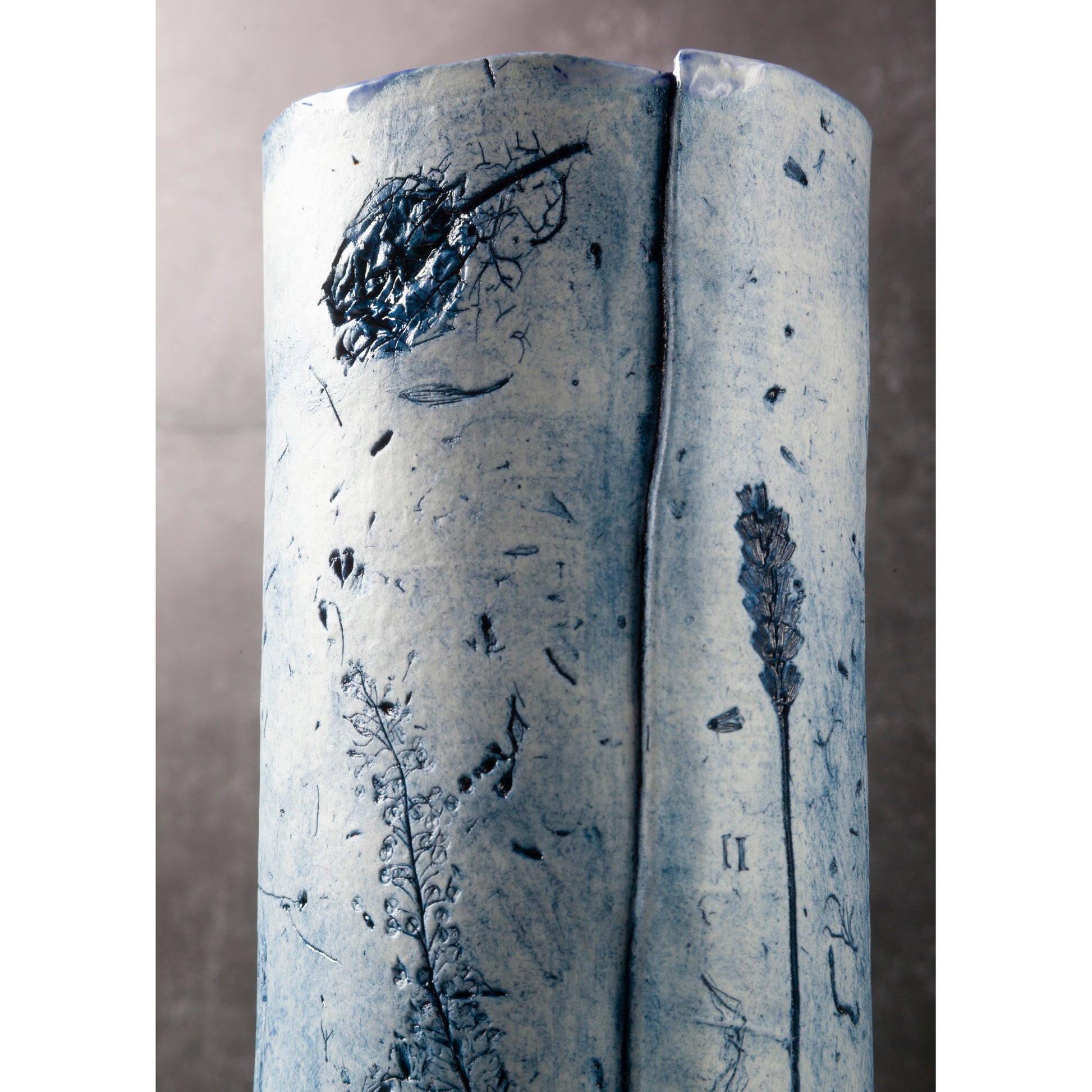 Cylindrical ceramic vase with floral patterns on a plain background