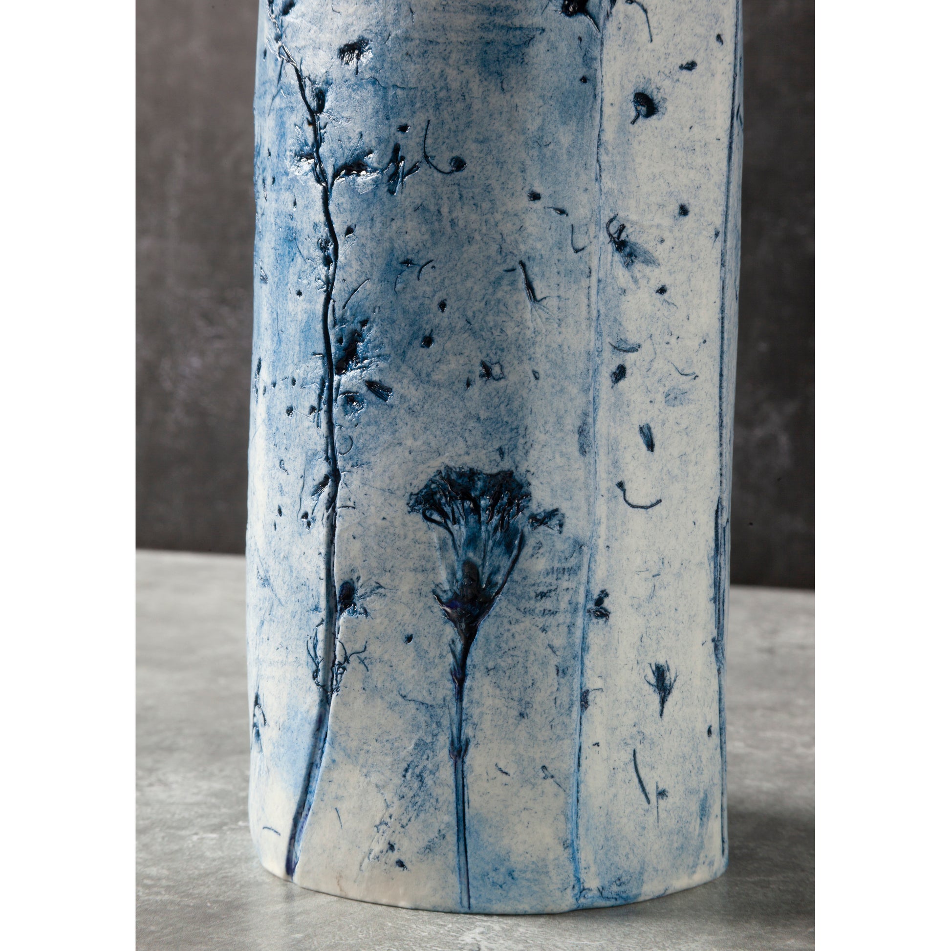 Cylindrical ceramic vase with blue floral patterns on a neutral background